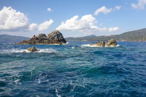 Rock reef with three rocks rising out of the sea Water above water surface Sea level off the coast