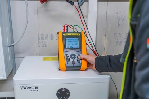 Person holds meter on a solar panel to check performance