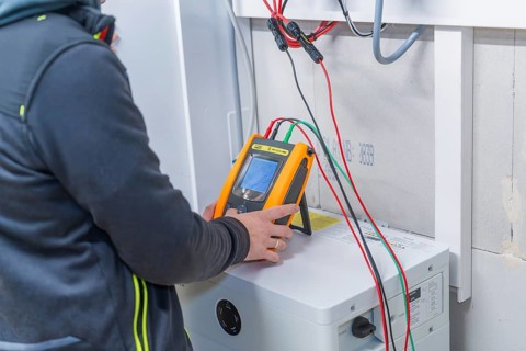 Technician checks solar system with measuring device device and cables in the device