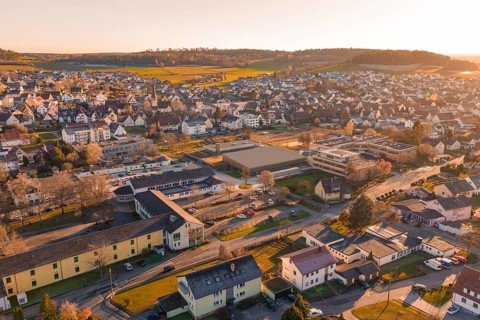 Aerial view of a settlement in warm evening light with hills and landscape in the background,