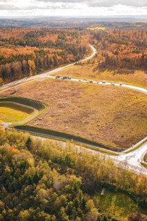 Autumn forest landscape crossed by a road next to a harvested field in sunlight, new Lindenrain