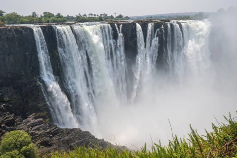 Water plunges into the depths, Victoria Falls with jungle and green plants, Zambezi, Zimbabwe