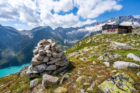 Mountain hut BergseehÃ¼tte with Swiss flag in picturesque mountain landscape, view of Damma Glacier