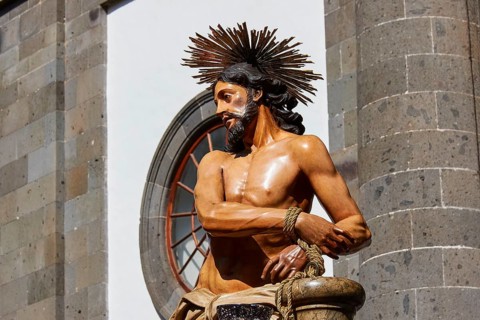 Good Friday procession, Christ statue in front of a stone building in sunlight, UNESCO World