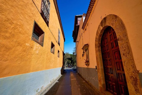 Narrow historic alley with yellow facades and wooden doors in the shade of a wall, UNESCO World