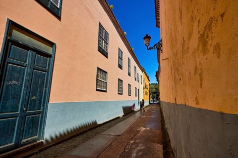 Narrow old town alleyway with pastel-colored houses and decorative alleyway lights, UNESCO World