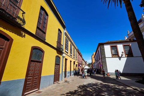 View along historic street with yellow facades and passers-by in sunny weather, UNESCO World
