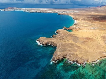 Coast with Playa de Papagayo beach and blue sea, arid landscape of Los Ajaches Natural Park, aerial