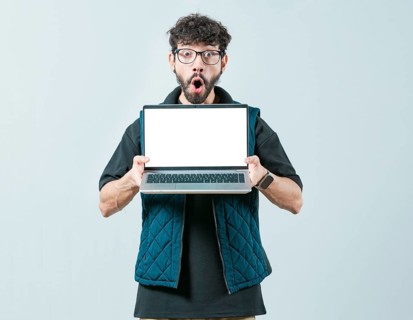 Surprised Handsome Man with glasses displaying a promotion on laptop screen. Portrait of bearded