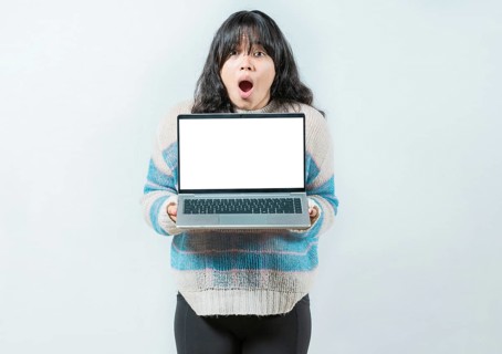 Portrait of beautiful asian girl showing laptop screen isolated. Young Asian woman displaying a