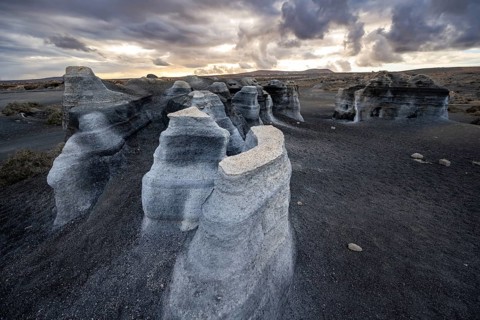 Eroded rock formations, volcanic landscape with dramatic cloudy sky at sunset, Ciudad Estratificada