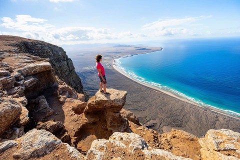 Woman enjoying the view from the Risco de Famara cliffs on Famara beach, Playa de Famara with La
