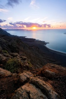 View from steep cliffs to sea and coast with sun stars, Mirador del Porrito viewpoint at sunset,