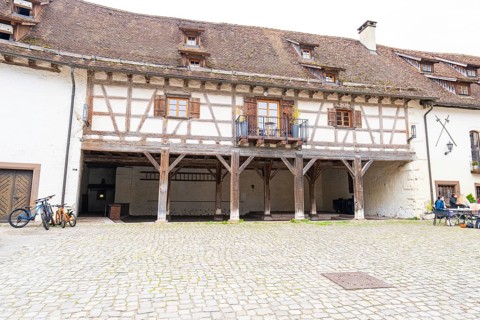 Historic courtyard with half-timbered balcony, paving stones, surrounded by traditional buildings,