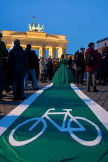 Athena Macke (costume designer) wears a dress with a long train in the shape of a bike path (bike