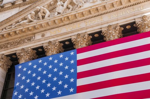 Facade of the New York Stock Exchange, stock exchange with USA national flag on Wall Street,