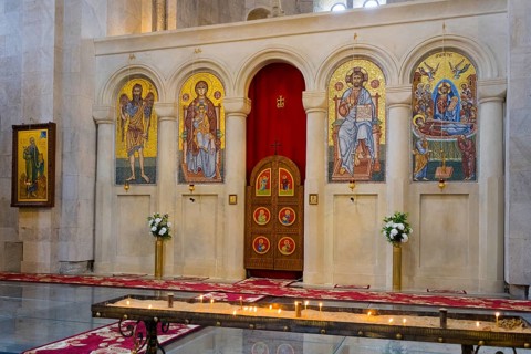 A magnificent church interior with mosaics and icons, candles standing in front of a decorated
