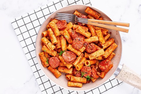 Rigatoni pasta with spicy sausage, and rich tomato sauce served, on a white plate, homemade