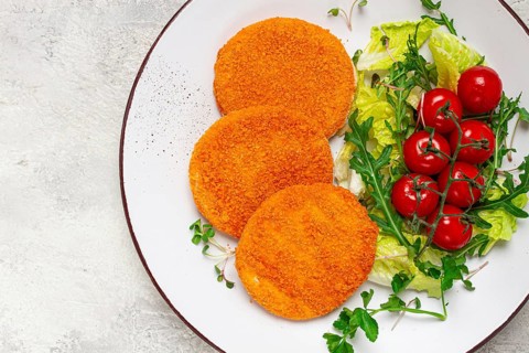 Crispy fried fish cutlets, fish burgers, on a white plate, with fresh lettuce leaves, arugula and