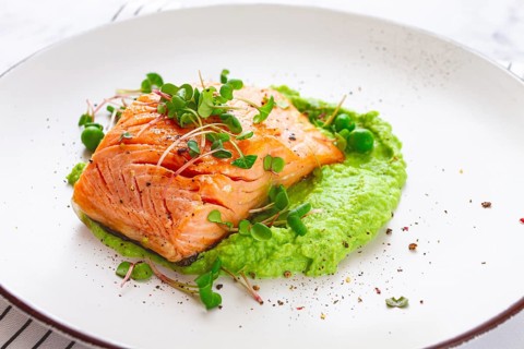 Delicious grilled salmon is placed elegantly on creamy green pea puree. Fresh microgreens and peas