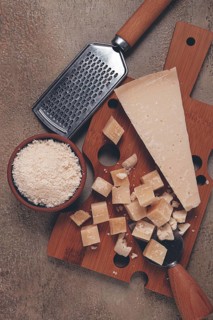 Freshly sliced and grated cheese, parmesan cheese, Gran gusto. Grana padano. on a wooden chopping