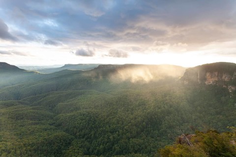 Evening sky with clouds of fog and setting sun at the Three Sisters at Echo Point in Katoomba, Blue