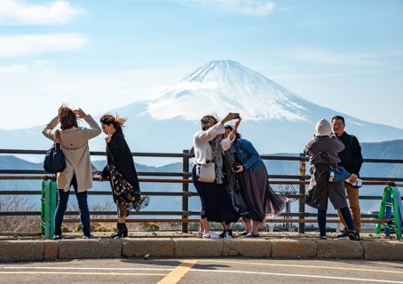 Tourists enjoy the view and take pictures, view of the snow-covered summit of Mount Fuji volcano in