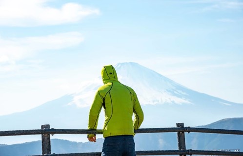 Tourist enjoying the view of the snow-covered summit of Mount Fuji volcano in spring, ÅŒwakudani,