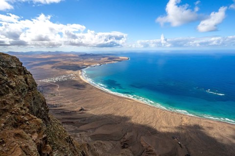 View from the Risco de Famara cliffs to the coast and the sea with the Famara beach, Playa de