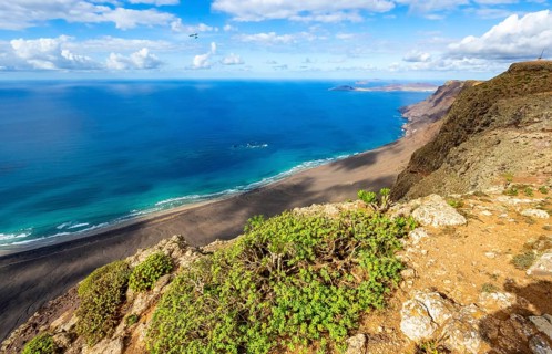 View from the Risco de Famara cliffs to the coast and the sea with the Famara beach, Playa de