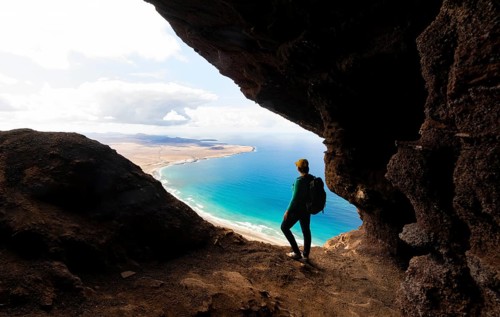 Tourist in the Cueva de las Cabras cave, young woman enjoying the view from the Risco de Famara