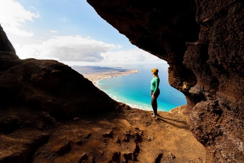 Tourist in the Cueva de las Cabras cave, young woman enjoying the view from the Risco de Famara