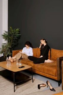 Two friends enjoy a cozy afternoon on a comfortable sofa in a modern living room. One reads