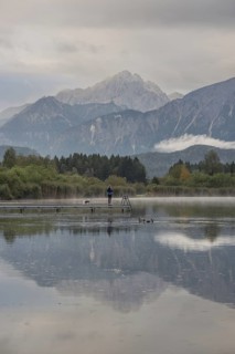 Woman (40-50) with dog on a wooden footbridge at sunrise, Hopfensee, near Füssen, Ostallgäu, behind