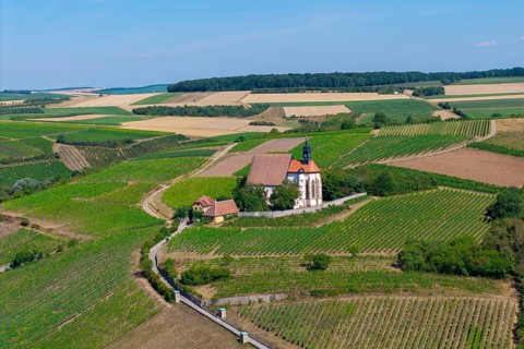 Pilgrimage church Maria im Weingarten, on a hill with surrounding fields under a blue sky, aerial