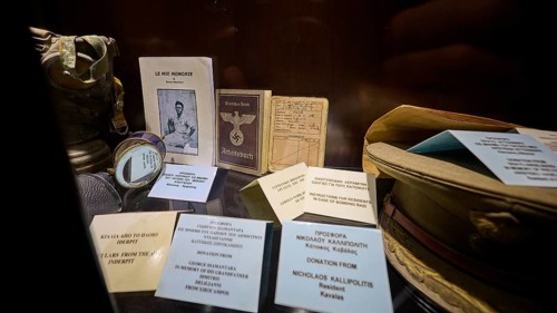 Display case with historical documents and memorabilia, including a book and pictures, workbook,