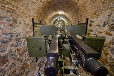 Two cannons displayed in a stone vault of a museum, machine gun, anti-aircraft gun, twin socketed