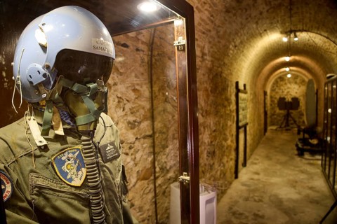 A helmet and pilot's suit behind glass in an illuminated tunnel, War Museum, Military Museum,