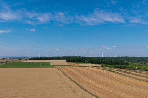 Wide fields with a wind farm on the horizon, under a clear blue sky, near Volkach, aerial view,