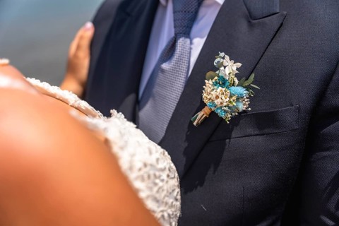 Groom wearing a dark suit with a boutonniere embracing the bride in a white dress during their