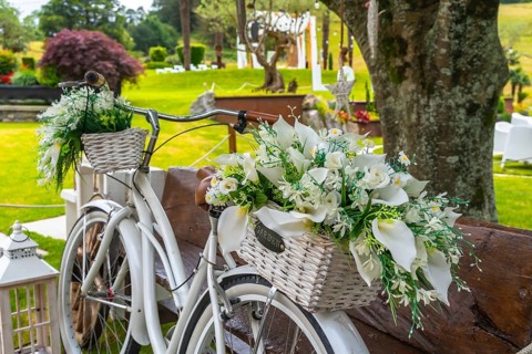 White vintage bicycle with wicker baskets full of white flowers, creating a romantic atmosphere for