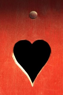 A heart-shaped cutout in a red wooden surface adds a whimsical touch. The contrasting dark interior