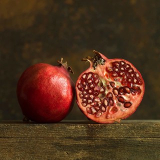 Pomegranate halves revealing juicy seeds on rustic wooden surface
