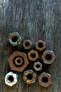 Collection of rusted metal nuts arranged on a weathered wooden surface highlighting unique textures