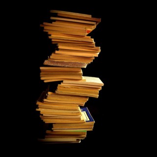Stack of neatly organized books arranged vertically against a dark backdrop highlighting their
