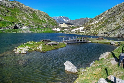 View of small island and simple wooden bridge in alpine lake Lac du Grand Gd Saint St Bernard, in