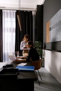 In a contemporary office, two women engage in a productive discussion while reviewing documents.
