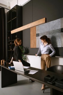 Two women engage in a productive discussion in a sleek office with dark walls and contemporary