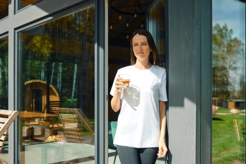 The woman went to the terrace of a country house with a glass of juice and enjoys silence and fresh