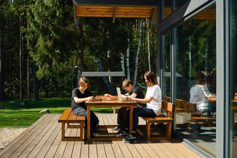 A single mother works remotely at a laptop sitting at a table on the terrace of a country house,
